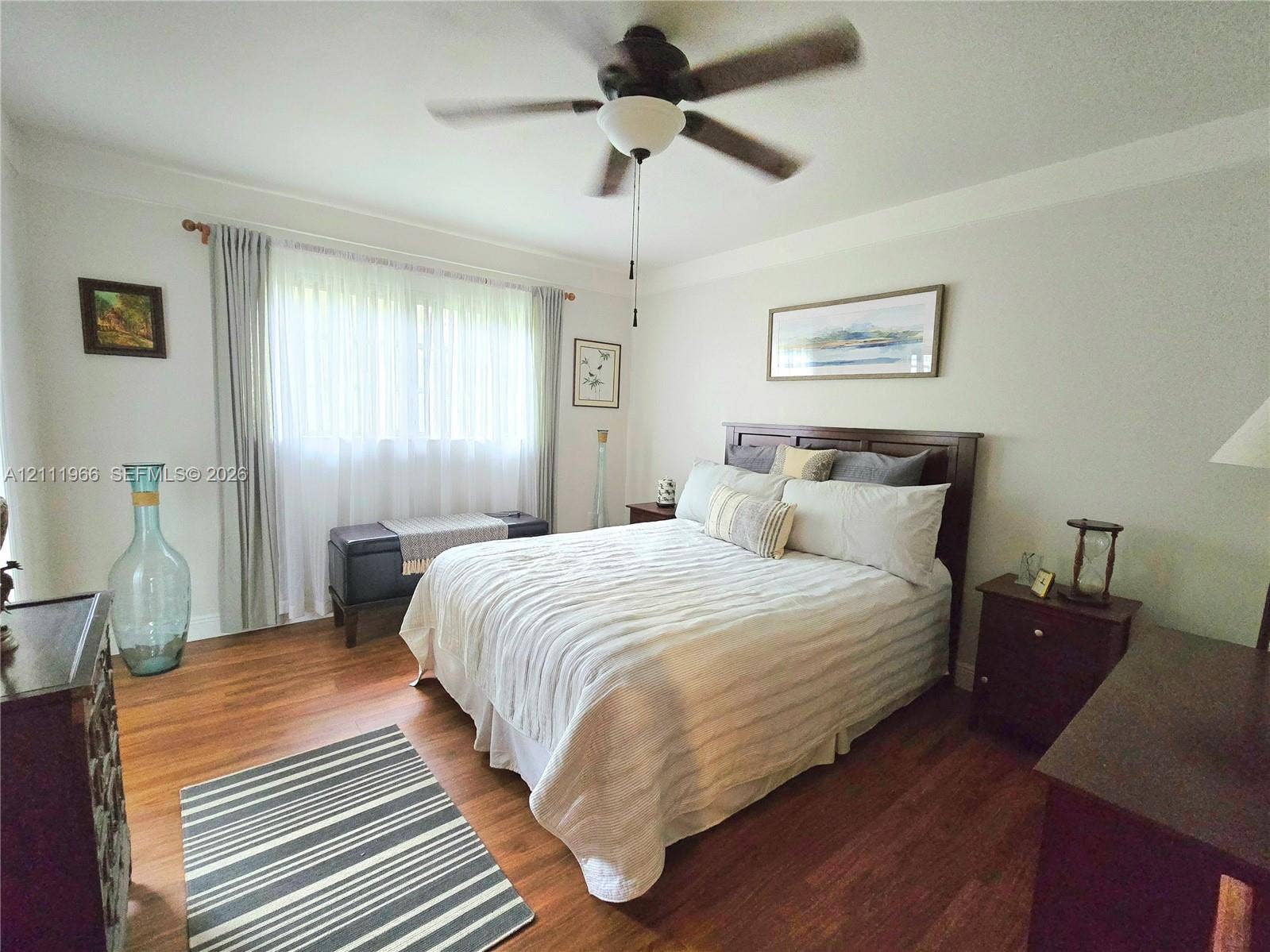 5387 SW 40th Avenue, #203, Dania Beach, FL 33314 Wood-finish flooring, multi-pane window with neutral drapery, and a ceiling-mounted fan with integrated lighting