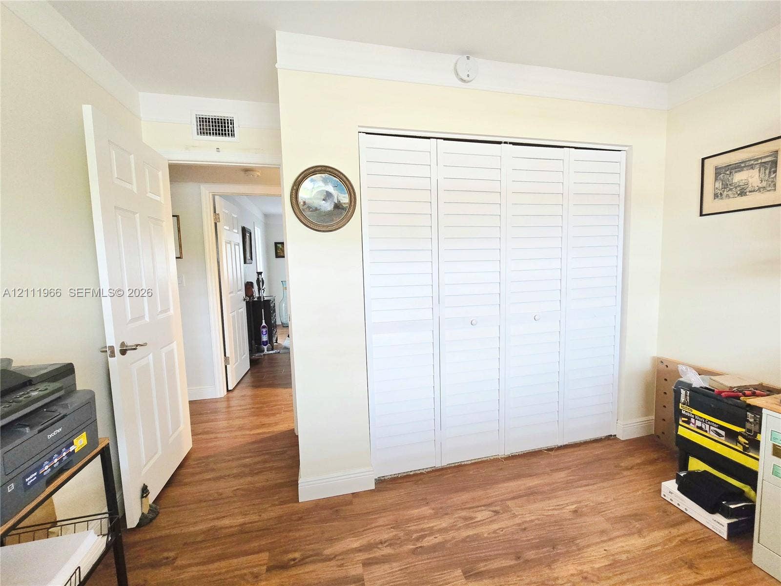 5387 SW 40th Avenue, #203, Dania Beach, FL 33314 Interior room featuring wood-finish flooring, white louvered closet doors, and a six-panel interior door