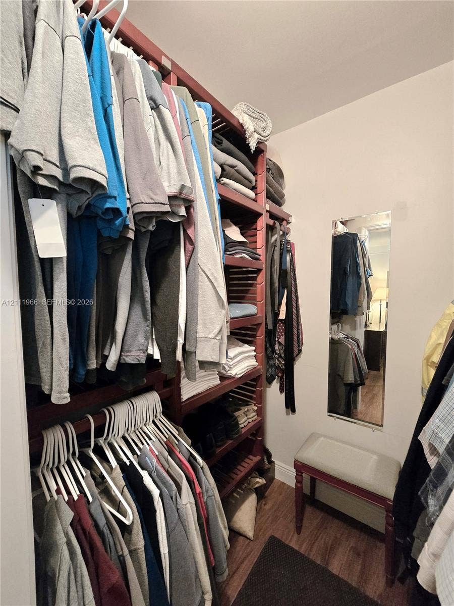 5387 SW 40th Avenue, #203, Dania Beach, FL 33314 Walk-in closet featuring floor-to-ceiling dark wood shelving, hanging rods, and wood-finish flooring