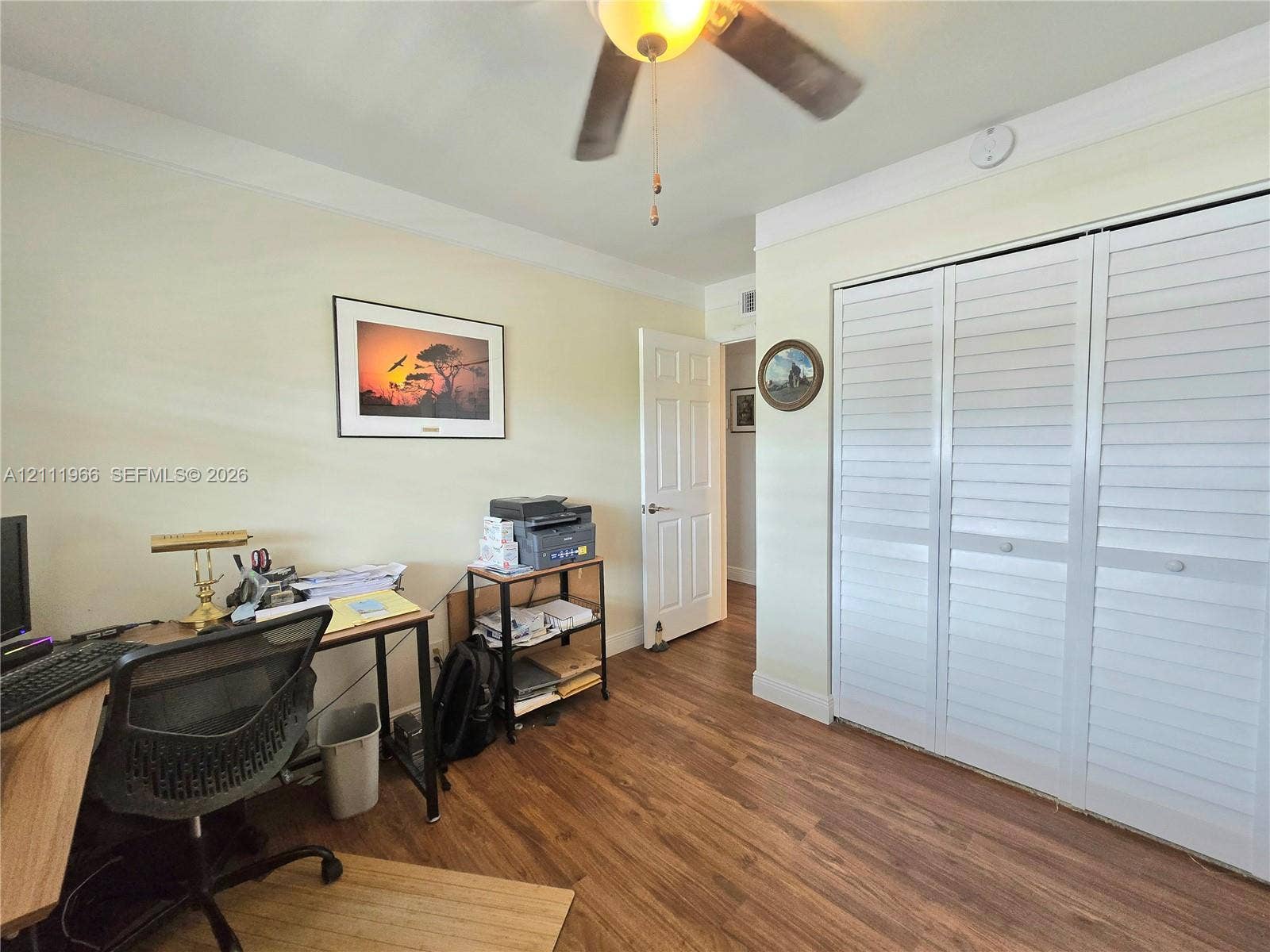 5387 SW 40th Avenue, #203, Dania Beach, FL 33314 Room featuring wood-finish flooring, white louvered-style closet doors, a ceiling fan with integrated lighting, and crown molding