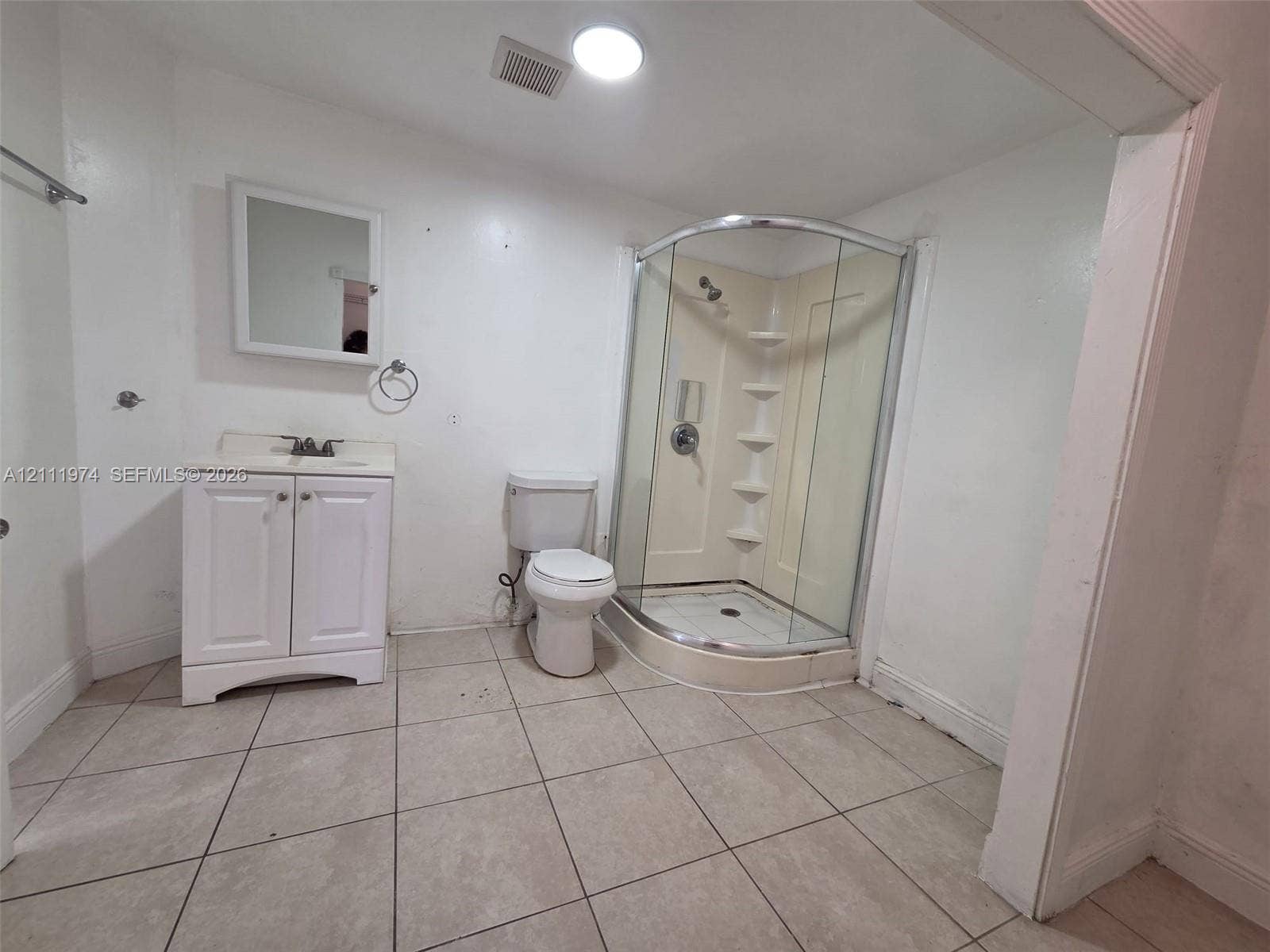 600 SW 44th Court, Miami, Miami, FL 33134 Bathroom featuring tile flooring, a white vanity cabinet with an integrated sink, a mirrored medicine cabinet, a toilet, and a curved glass-enclosed shower stall with built-in shelving