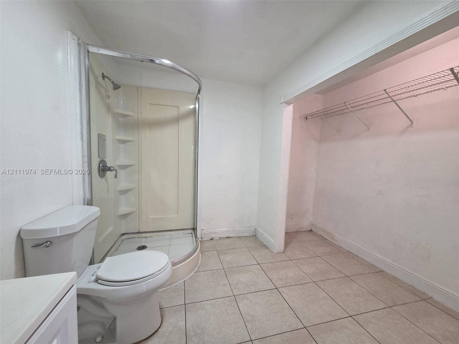 600 SW 44th Court, Miami, Miami, FL 33134 Curved glass shower enclosure with integrated shelving, tile flooring, and built-in wire closet shelving