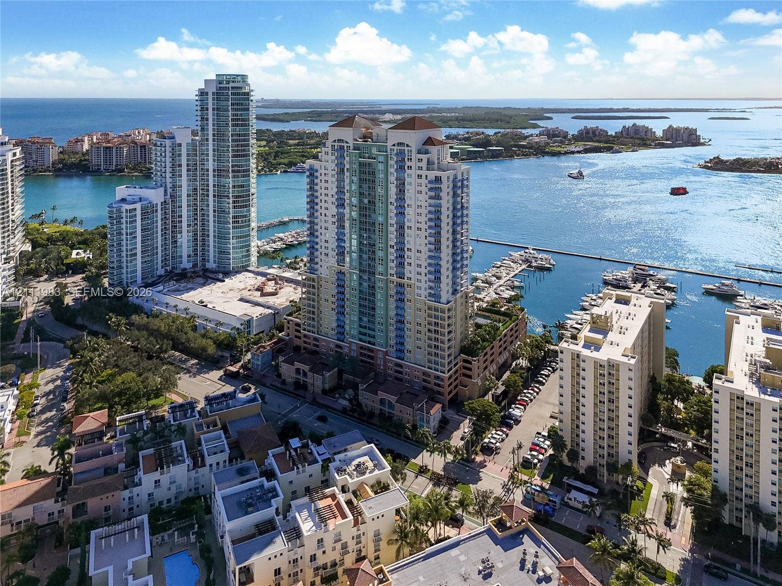 90 Alton Road, #TH-8, Miami Beach, FL 33139 High-rise residential tower featuring a multi-story glass and concrete facade, situated on a waterfront lot with deep-water boat slips and a peripheral parking structure