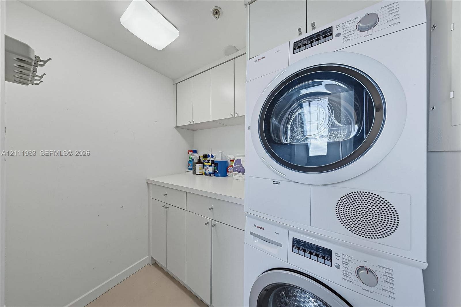 90 Alton Road, #TH-8, Miami Beach, FL 33139 Laundry space featuring stacked front-load washer and dryer, solid-surface countertop, and extensive built-in white cabinetry