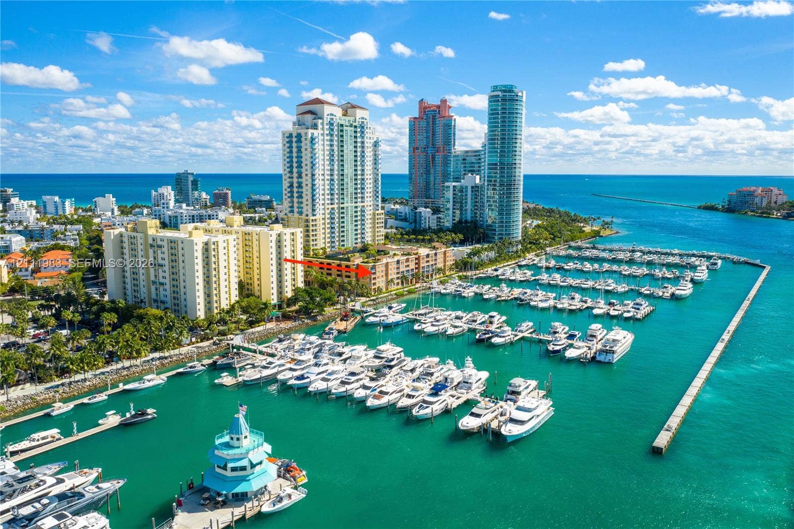 90 Alton Road, #TH-8, Miami Beach, FL 33139 Aerial perspective of a high-rise residential building situated on a waterfront marina featuring multiple boat slips and docking facilities
