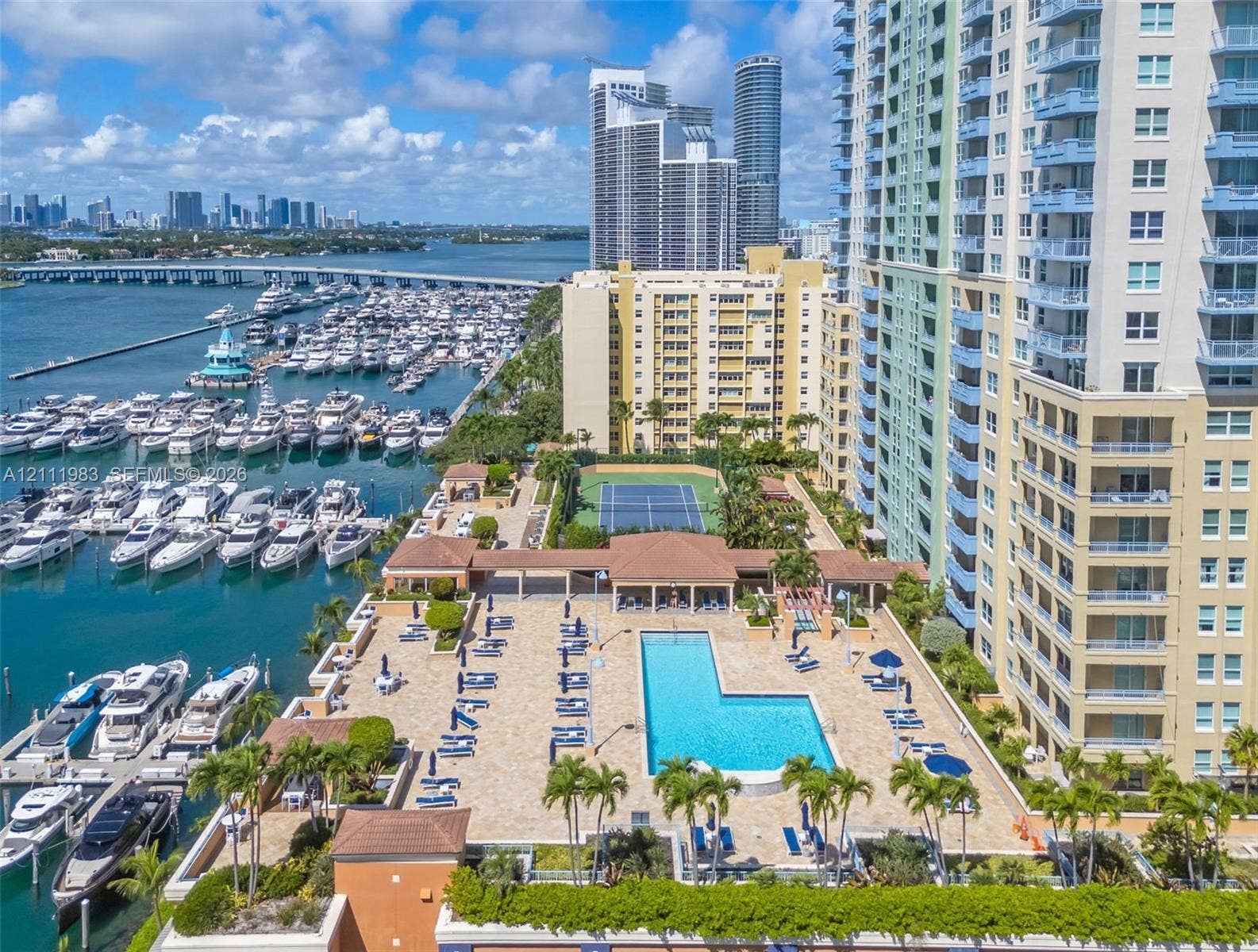 90 Alton Road, #TH-8, Miami Beach, FL 33139 Outdoor recreational area featuring a paved pool deck, swimming pool, and tennis court, situated directly on a deep-water marina