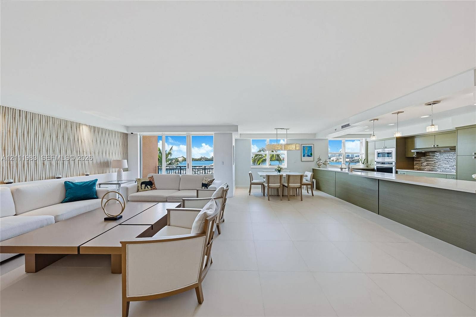90 Alton Road, #TH-8, Miami Beach, FL 33139 Open-concept living space featuring large-format tile flooring, textured accent wall, integrated kitchen cabinetry, stainless steel built-in appliances, and expansive glass sliding doors