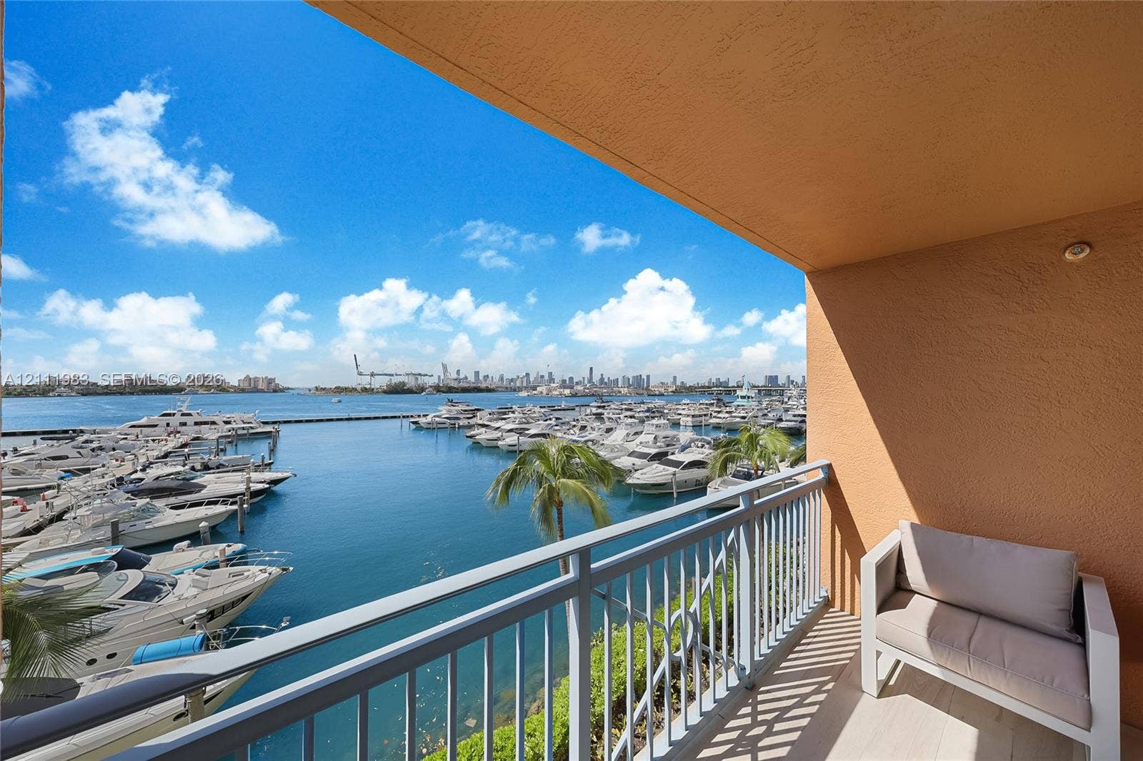90 Alton Road, #TH-8, Miami Beach, FL 33139 Covered balcony featuring stucco walls, metal railings, and stone-finish flooring, overlooking a marina and city skyline