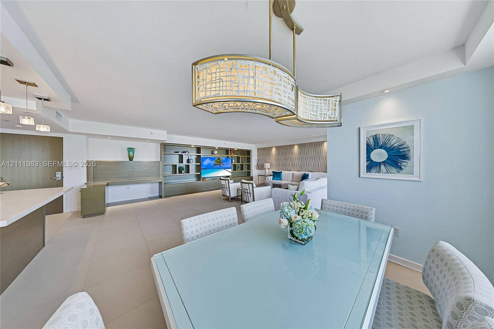 90 Alton Road, #TH-8, Miami Beach, FL 33139 Open-concept space featuring large-format tile flooring, a custom built-in media wall, recessed ceiling lighting, and an ornate, multi-tiered metal and glass pendant light fixture