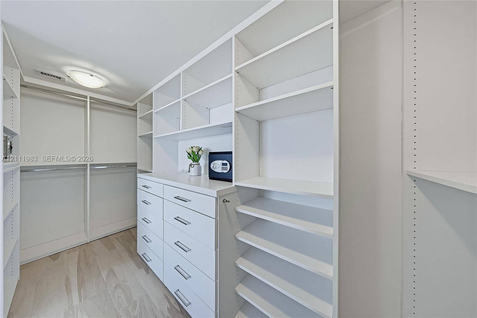 90 Alton Road, #TH-8, Miami Beach, FL 33139 Walk-in closet featuring extensive built-in white cabinetry, multiple tiered shelving units, integrated drawer storage, and light-tone wood-finish flooring