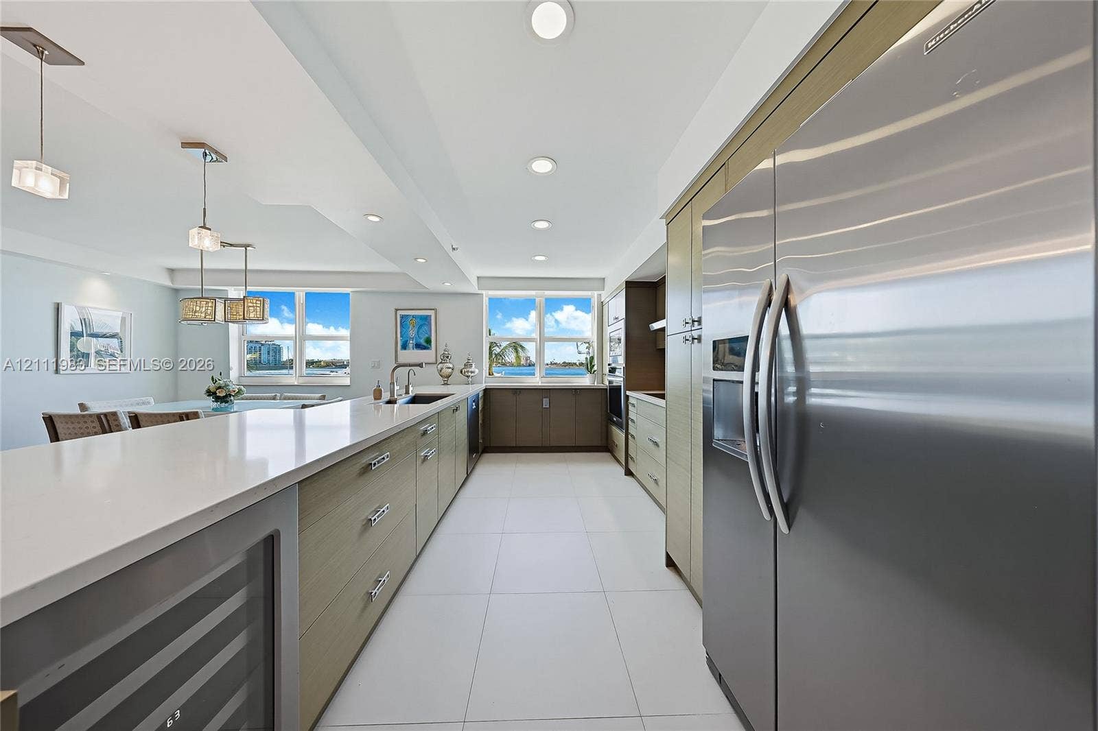 90 Alton Road, #TH-8, Miami Beach, FL 33139 Kitchen featuring stainless steel appliances, flat-panel cabinetry, a long island with a solid-surface countertop, tile flooring, and integrated wine refrigeration