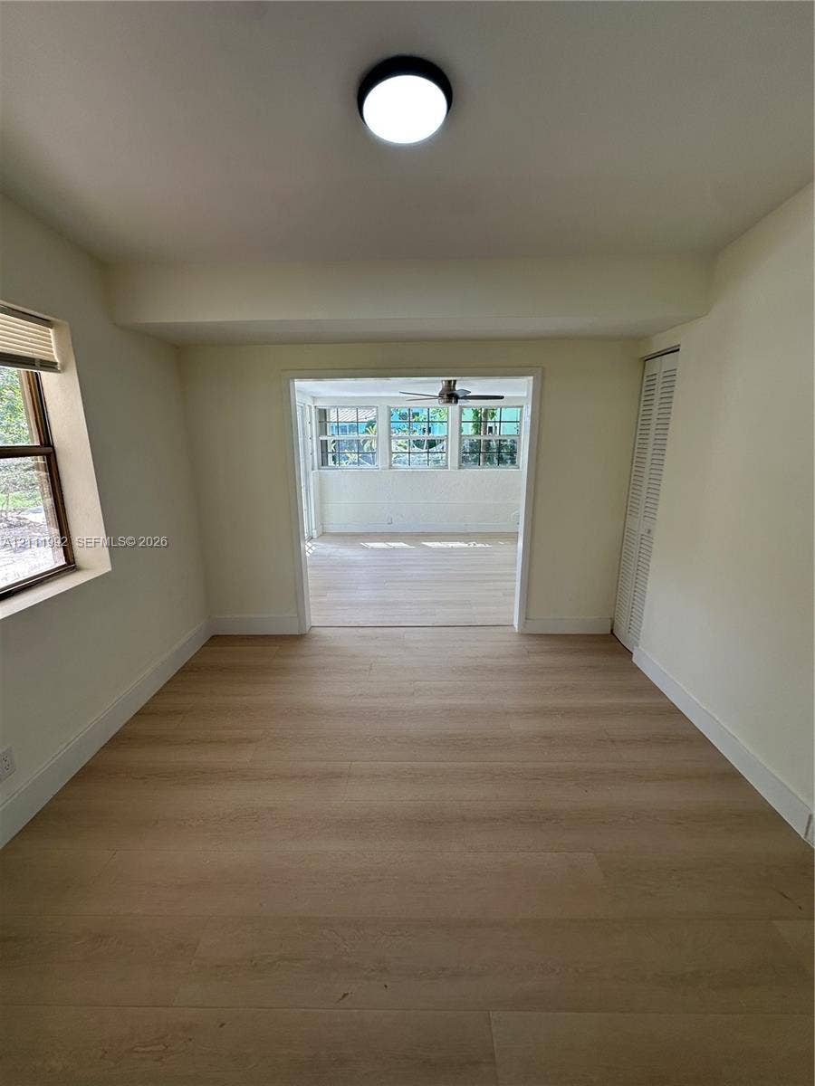 Neutral-toned interior featuring wood-finish flooring, a flush-mount overhead light fixture, bi-fold closet doors, and multi-pane windows