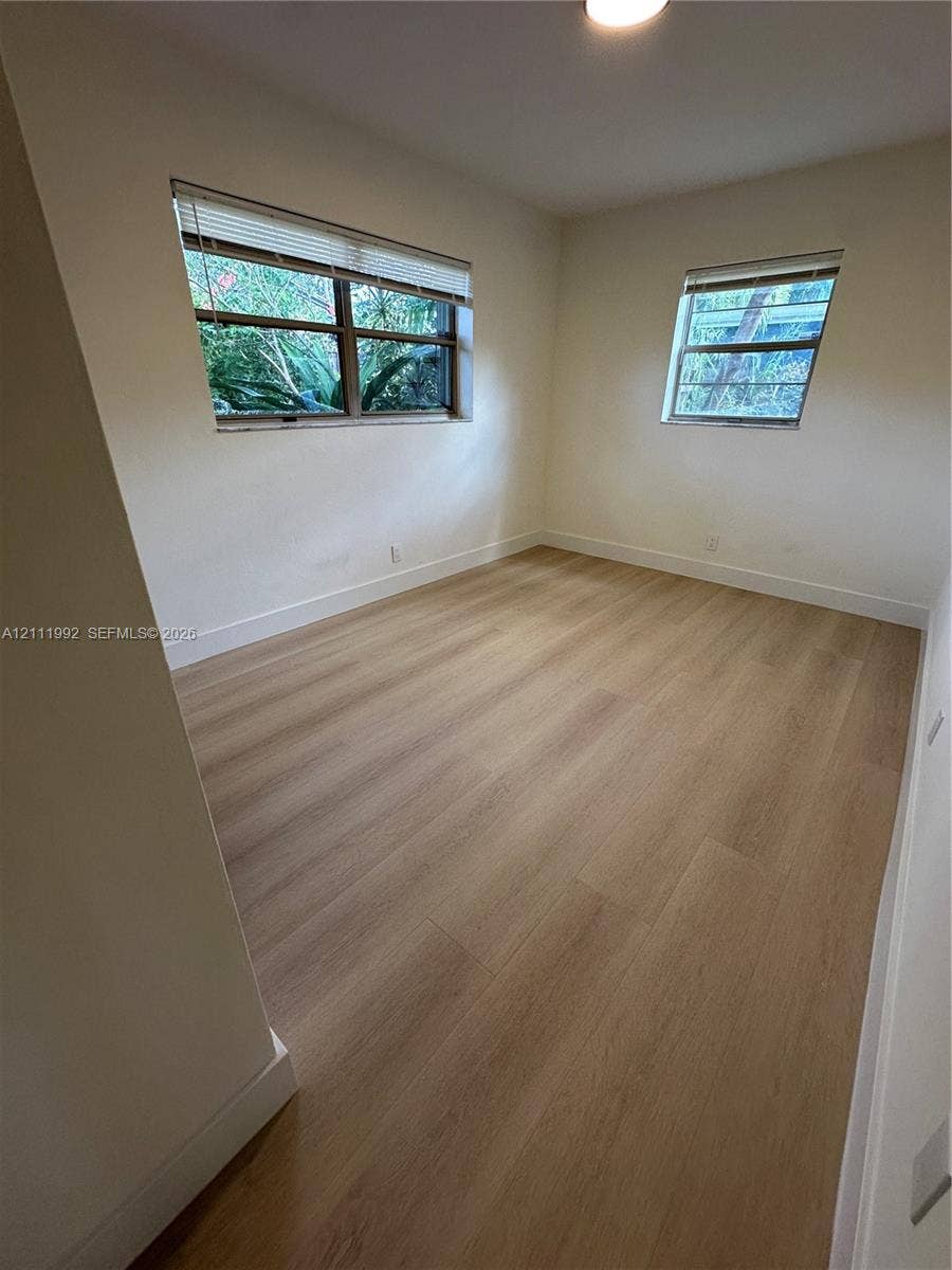 Neutral wall tones, wood-finish flooring, and multiple windows with integrated blinds
