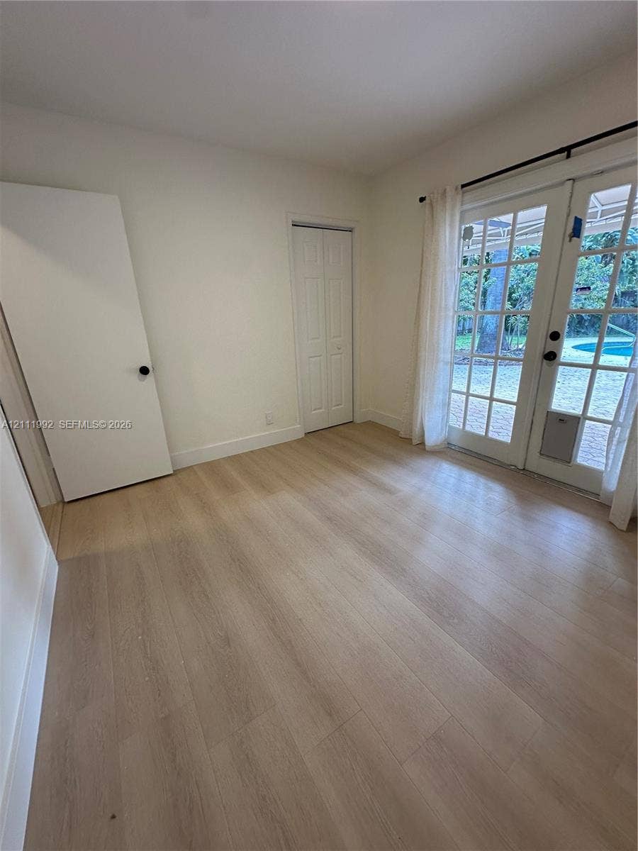Interior space featuring wood-finish flooring, white walls, bifold closet doors, and French doors with glass panes