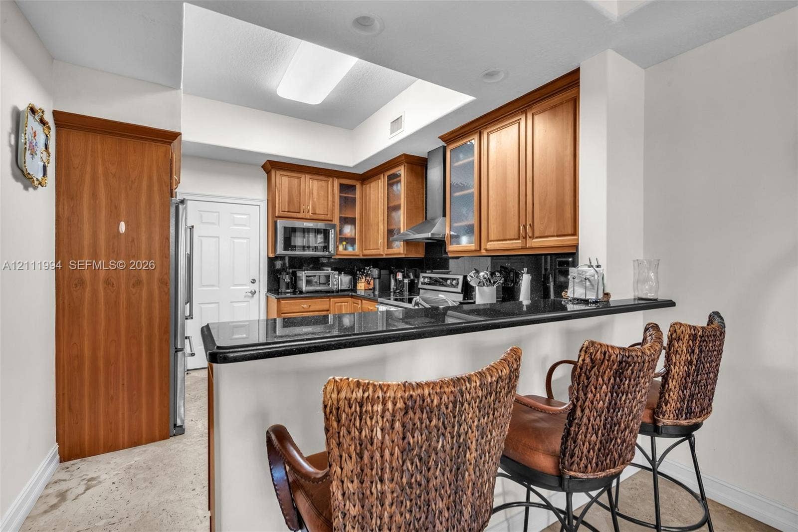 Kitchen featuring wood cabinetry, stone countertops, breakfast bar, recessed lighting, and stainless steel appliances