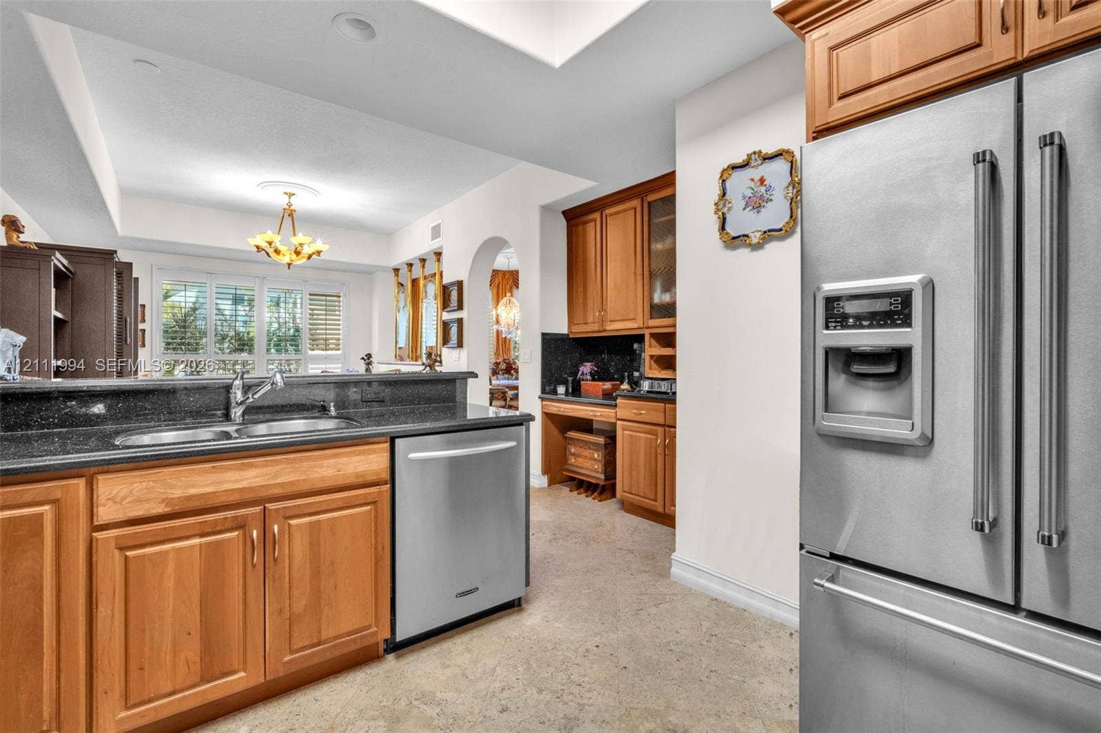 Kitchen featuring natural wood cabinetry, dark stone countertops, stainless steel appliances, a double-basin sink, and recessed lighting