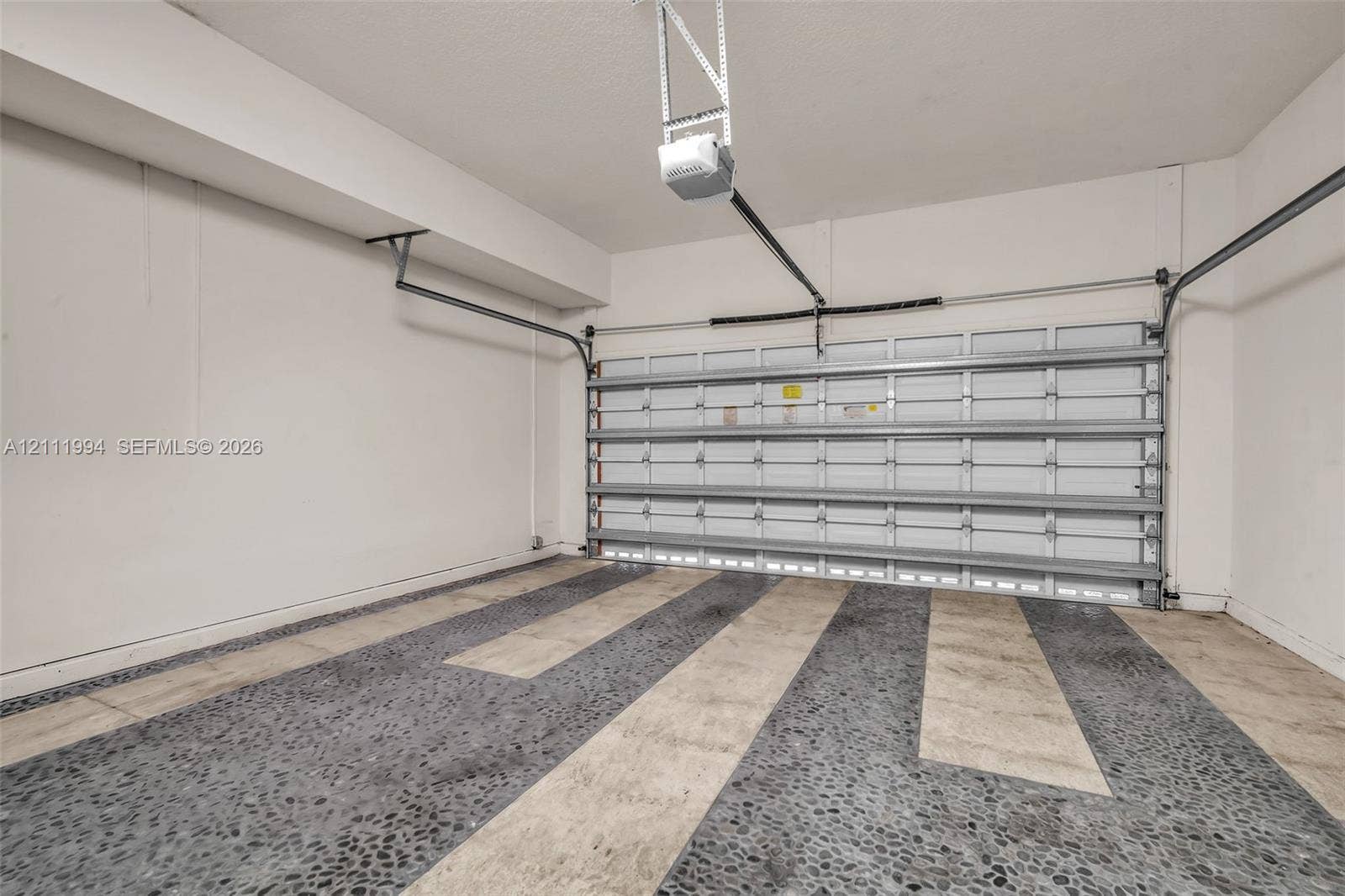 Garage featuring smooth-finish walls, a steel sectional door, and decorative aggregate concrete flooring