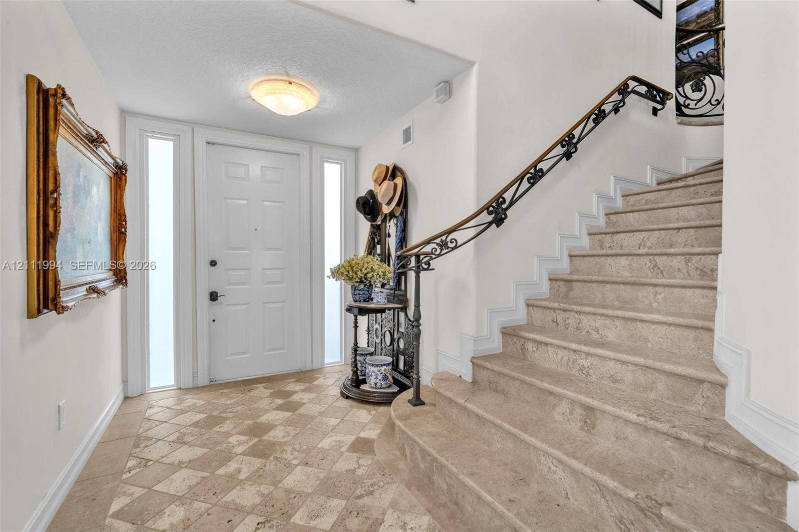 Entryway featuring stone tile flooring, a paneled door with dual sidelights, a custom iron handrail, and stone stairs
