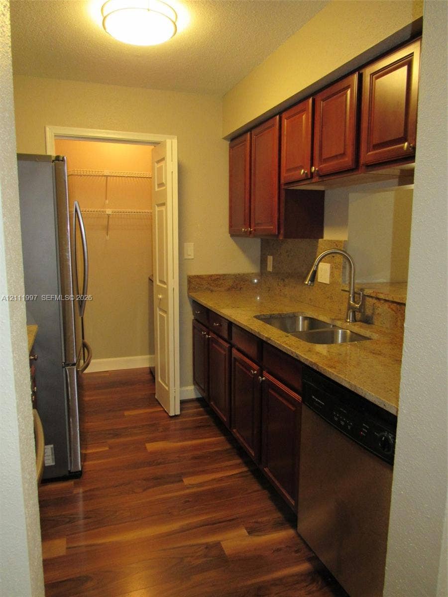 733 Riverside Drive, #1232, Coral Springs, Coral Springs, FL 33071 Kitchen featuring dark-toned cabinetry, natural stone countertops, stainless steel appliances, wood-finish flooring, and a walk-in pantry