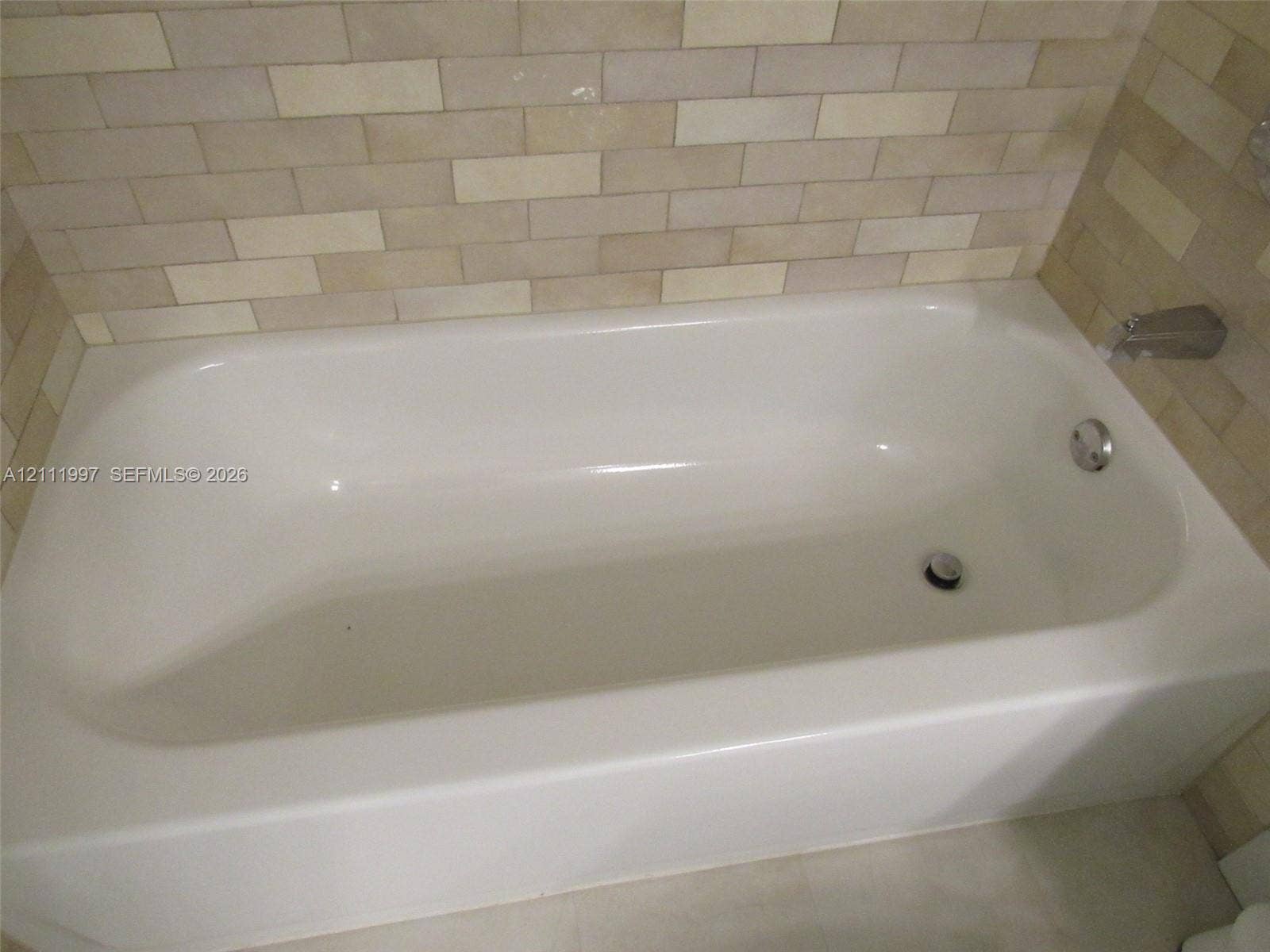 733 Riverside Drive, #1232, Coral Springs, Coral Springs, FL 33071 Built-in soaking tub with a smooth, white finish, chrome-plated hardware, and neutral-toned rectangular wall tile