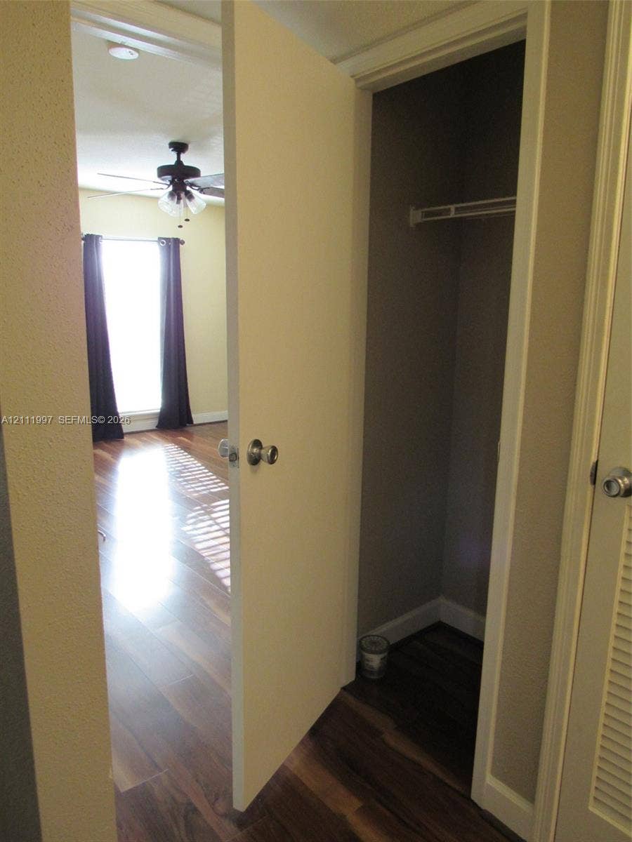 733 Riverside Drive, #1232, Coral Springs, Coral Springs, FL 33071 Interior space featuring wood-finish flooring, a built-in closet with overhead shelving, and a ceiling fan with integrated lighting
