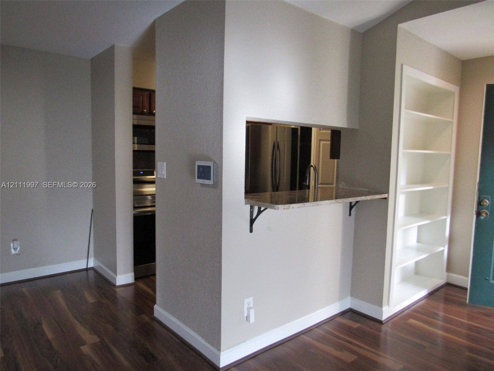 733 Riverside Drive, #1232, Coral Springs, Coral Springs, FL 33071 Built-in shelving unit, wood-finish flooring, pass-through opening with a stone countertop, and stainless steel kitchen appliances