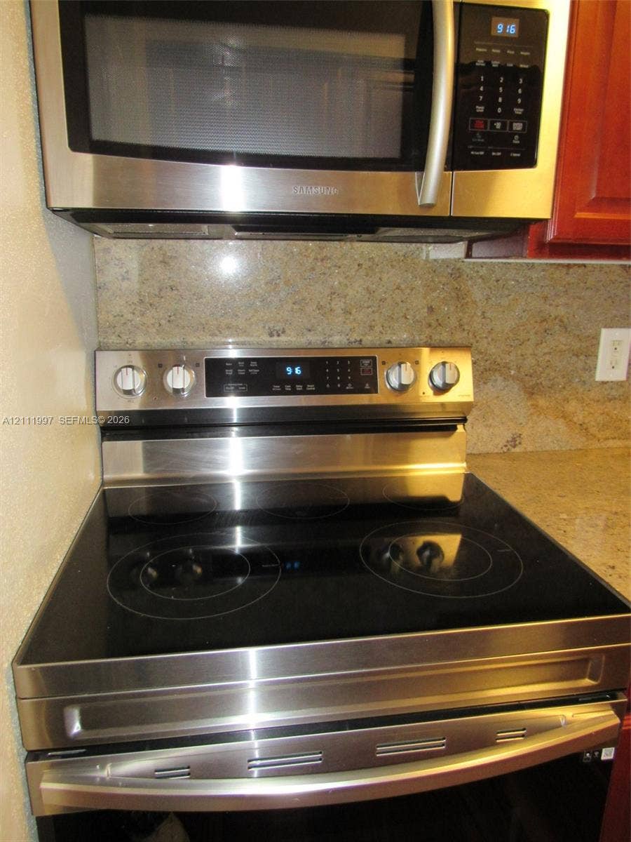 733 Riverside Drive, #1232, Coral Springs, Coral Springs, FL 33071 Stainless steel over-the-range microwave and electric range with a glass cooktop, paired with a solid-surface backsplash and countertop