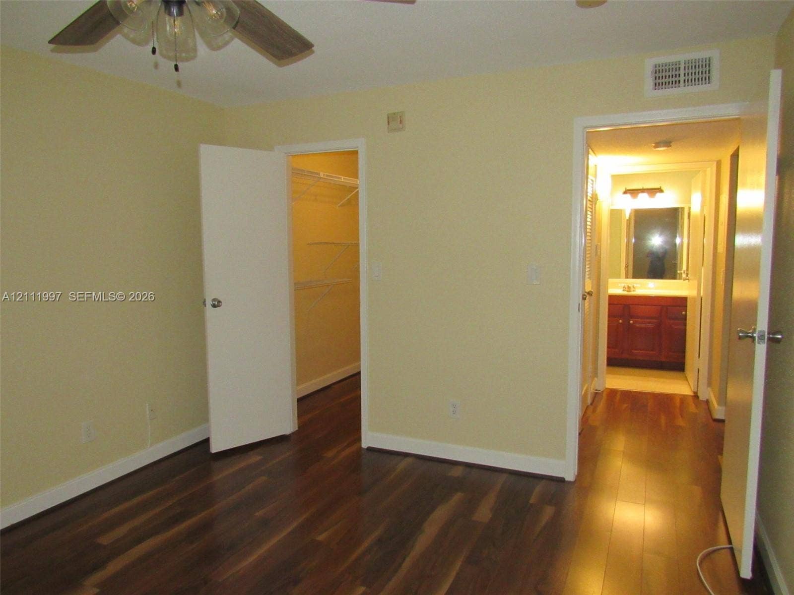 733 Riverside Drive, #1232, Coral Springs, Coral Springs, FL 33071 Wood-finish flooring, ceiling fan with integrated light fixture, walk-in closet with wire shelving, and bathroom featuring vanity cabinetry