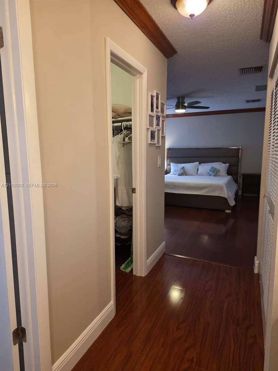 Wood-finish flooring, crown molding, and a louvered closet door