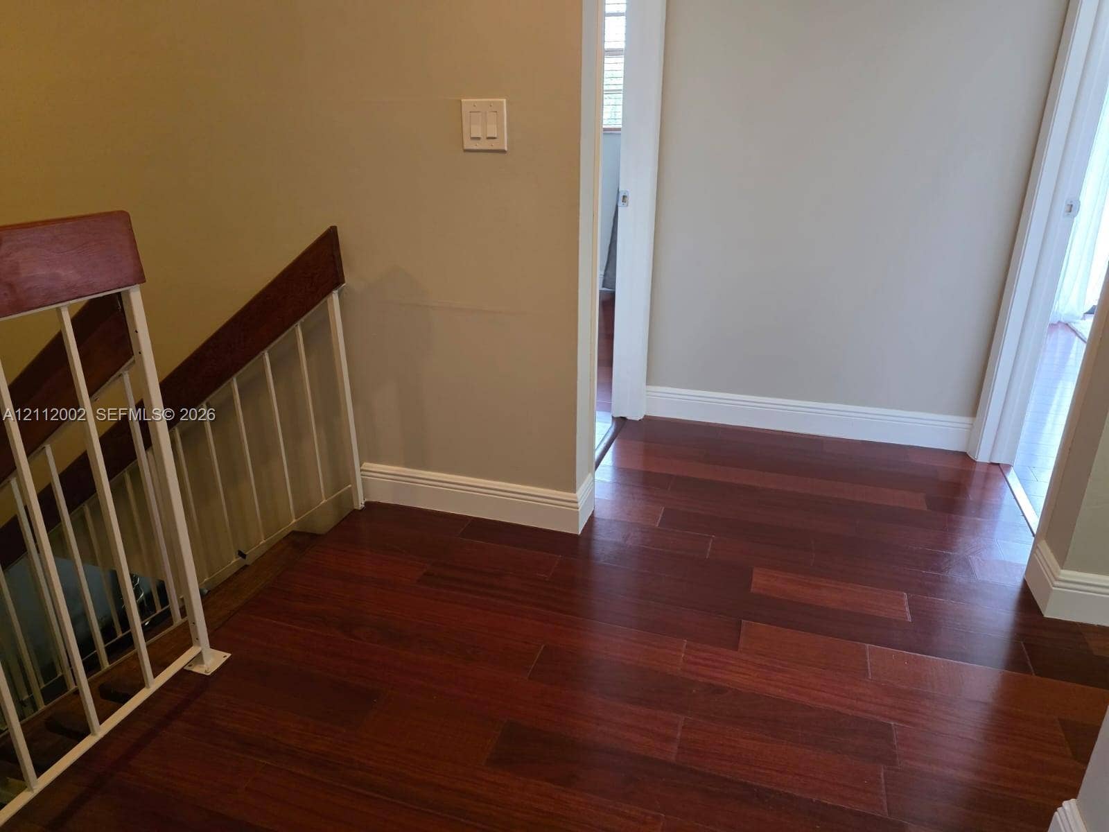 Wood-finish flooring, staircase with metal balusters, and wood-capped handrail