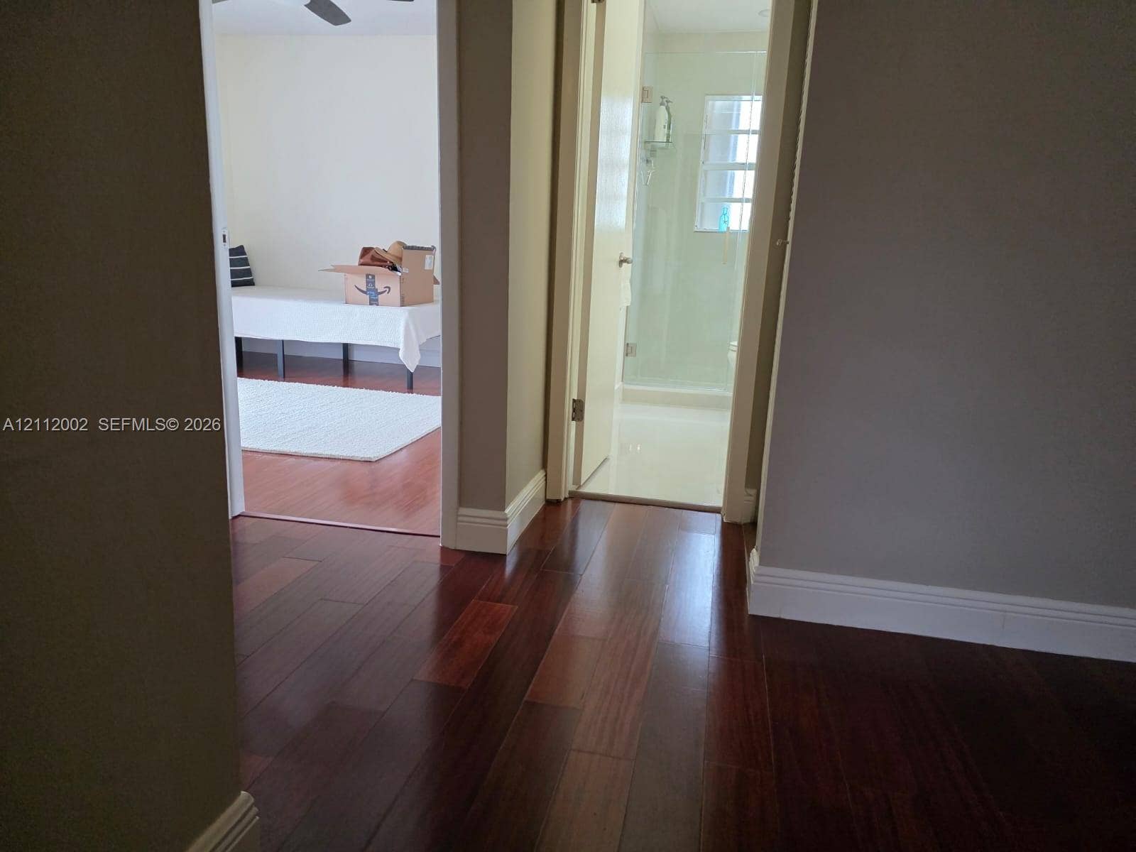 Rich-toned wood-finish flooring, glass-enclosed shower, and neutral wall tones