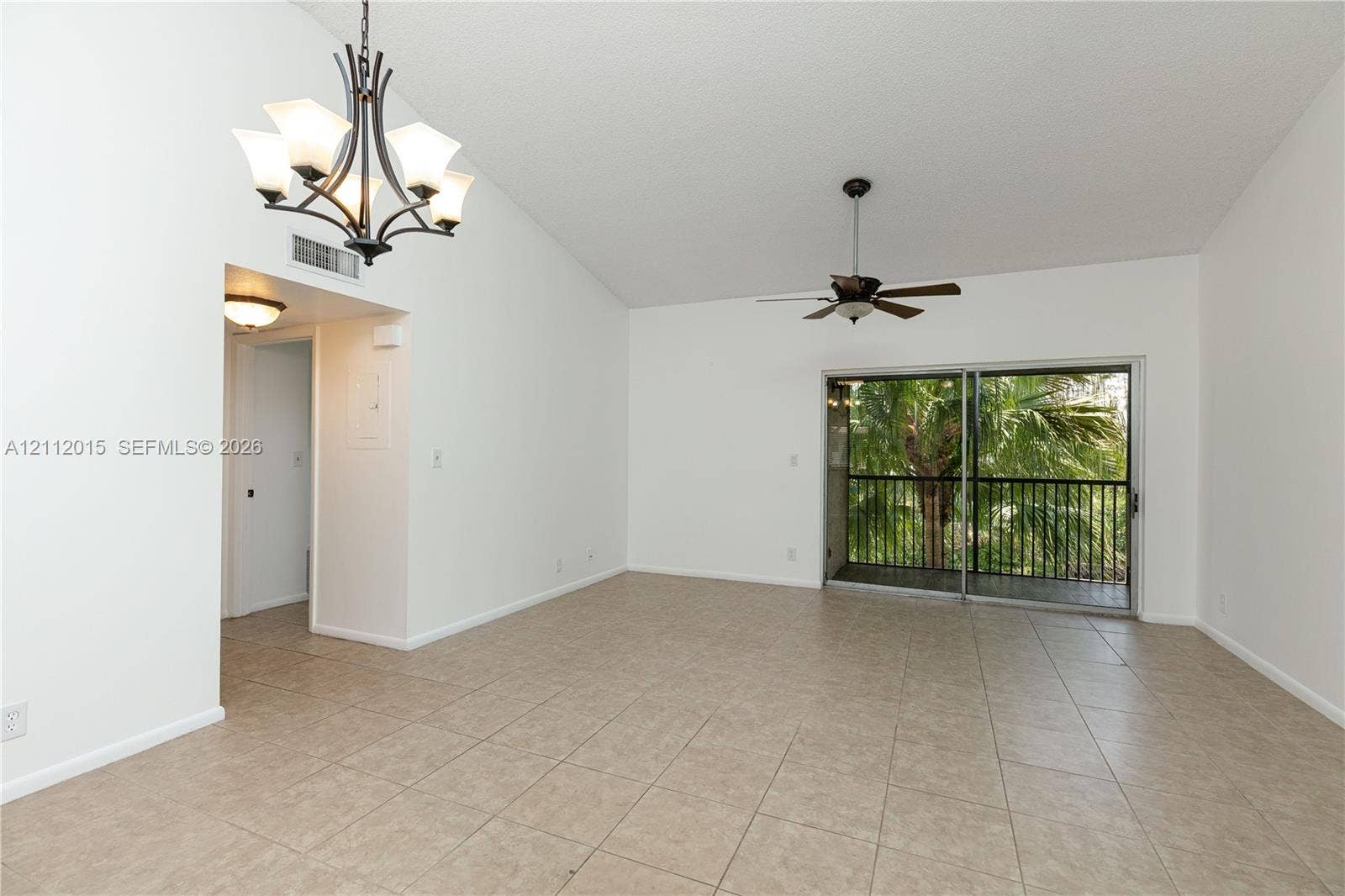 717 Gardens Drive, #201, Pompano Beach, Pompano Beach, FL 33069 Vaulted ceilings, neutral tile flooring, multi-light iron chandelier, ceiling fan, and sliding glass door leading to a railed balcony