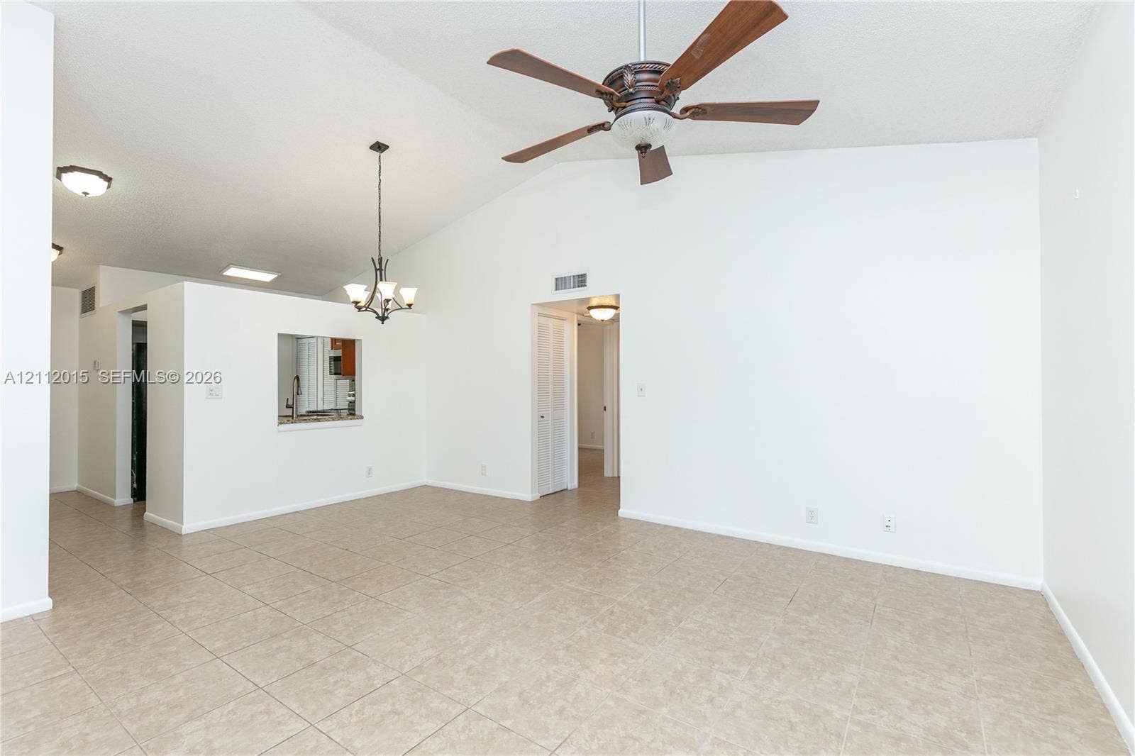717 Gardens Drive, #201, Pompano Beach, Pompano Beach, FL 33069 Vaulted ceilings featuring a central ceiling fan, neutral tile flooring, a decorative chandelier, and a kitchen pass-through window