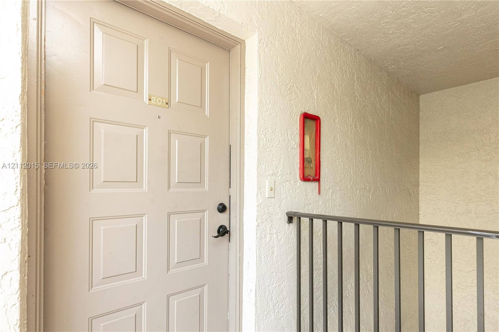 717 Gardens Drive, #201, Pompano Beach, Pompano Beach, FL 33069 Entryway featuring a solid-core, six-panel door with integrated lock hardware and a textured stucco wall finish