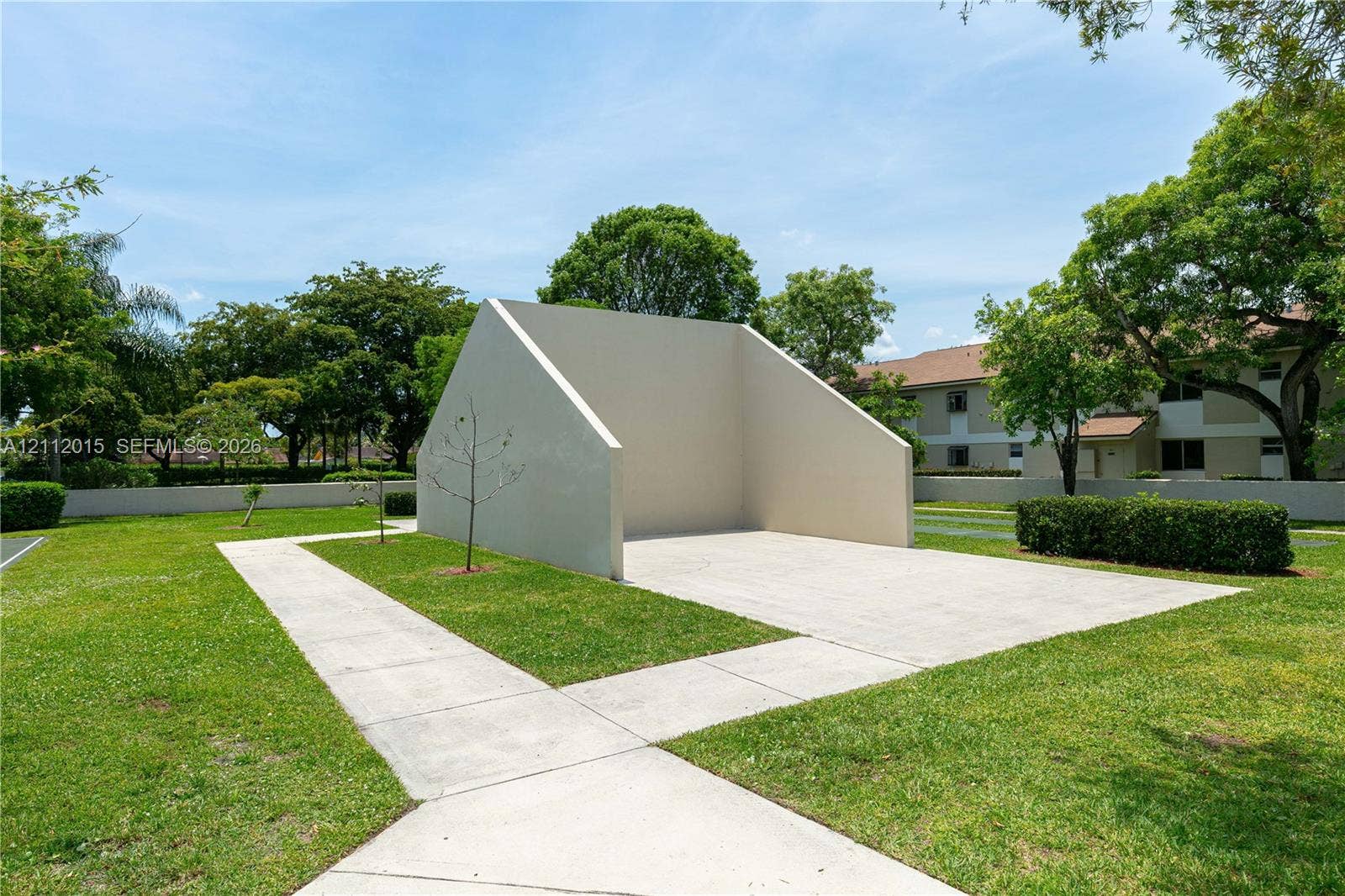 717 Gardens Drive, #201, Pompano Beach, Pompano Beach, FL 33069 Handball court featuring a concrete surface and a solid stucco-finish backboard situated within a lawn area with paved pathways