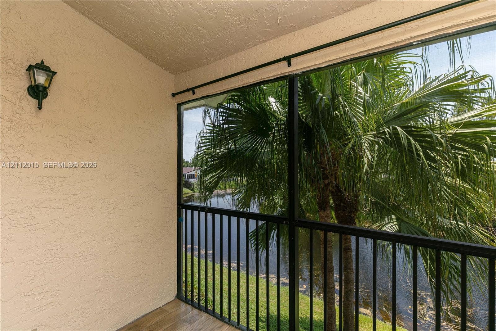 717 Gardens Drive, #201, Pompano Beach, Pompano Beach, FL 33069 Covered porch featuring wood-finish flooring, stucco walls, attached exterior wall-mounted lighting, and a screened-in enclosure with metal railings