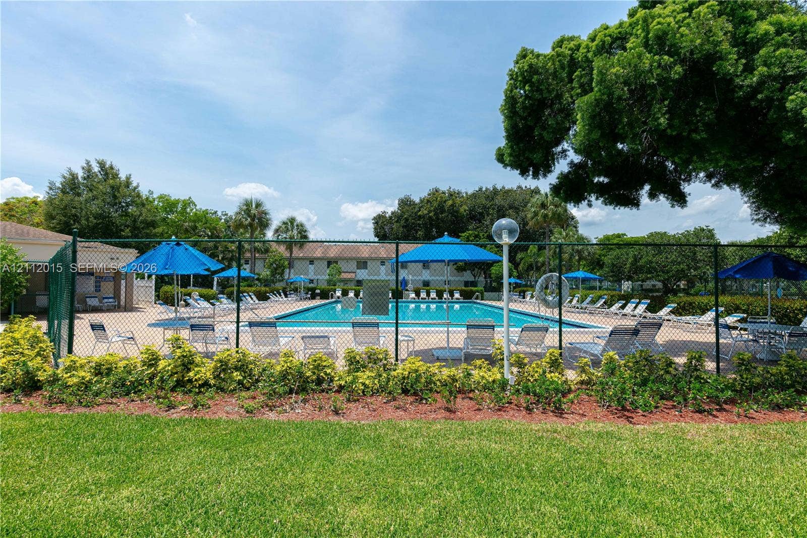 717 Gardens Drive, #201, Pompano Beach, Pompano Beach, FL 33069 Swimming pool with a paved deck, perimeter fencing, mature landscaping, and green space