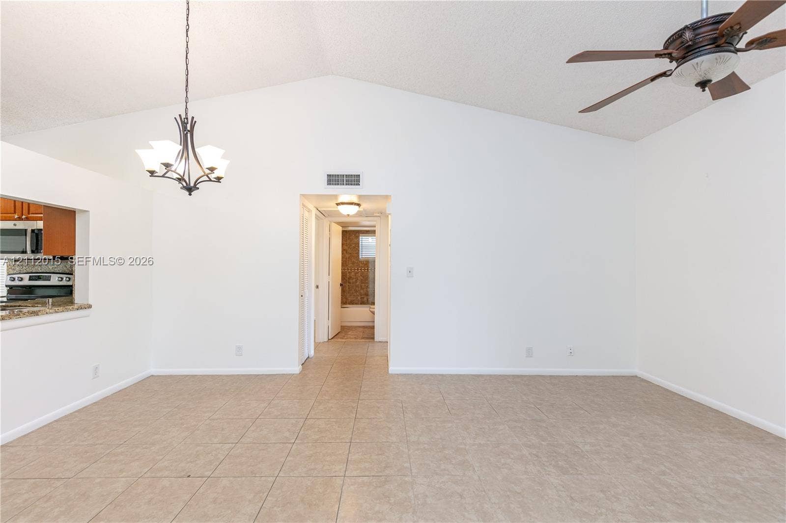 717 Gardens Drive, #201, Pompano Beach, Pompano Beach, FL 33069 Vaulted ceiling featuring a central multi-light chandelier and a multi-blade ceiling fan, finished with ceramic tile flooring