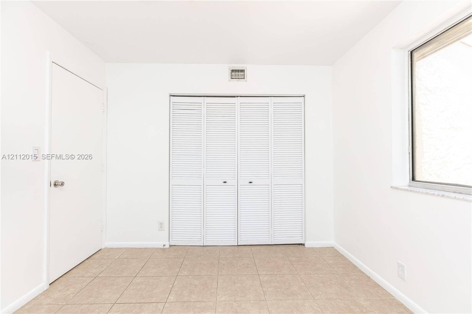 717 Gardens Drive, #201, Pompano Beach, Pompano Beach, FL 33069 Interior space featuring neutral tile flooring, a four-panel louvered closet, and a single-hung window with a stone-finish sill