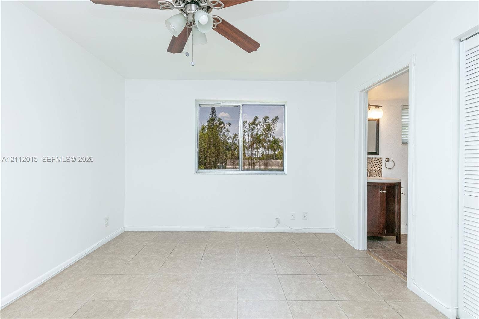 717 Gardens Drive, #201, Pompano Beach, Pompano Beach, FL 33069 Room featuring neutral tile flooring, a central ceiling fan with integrated lighting, a sliding window, and a louvered closet door