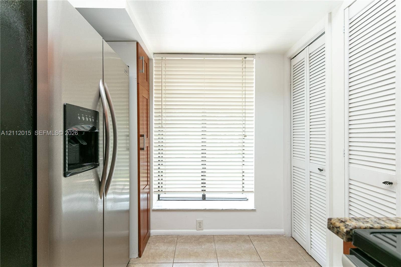 717 Gardens Drive, #201, Pompano Beach, Pompano Beach, FL 33069 Stainless steel side-by-side refrigerator, built-in wooden cabinetry, tile flooring, and white louvered closet doors