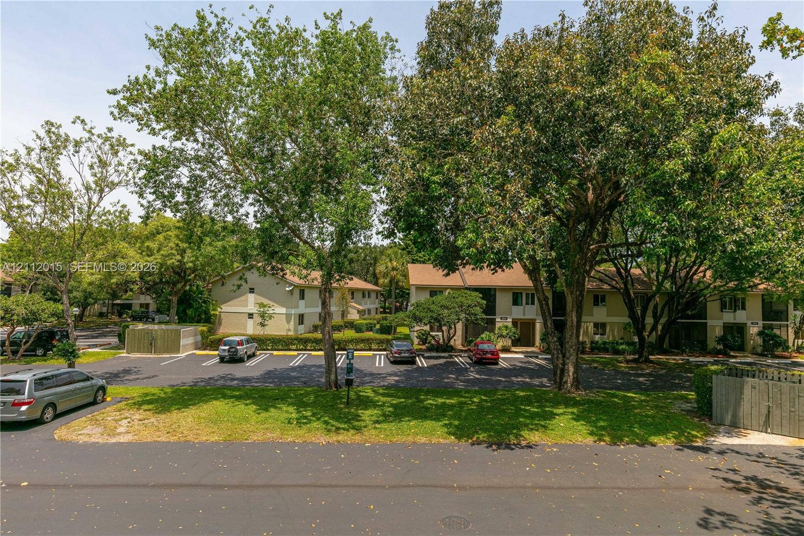 717 Gardens Drive, #201, Pompano Beach, Pompano Beach, FL 33069 Exterior view featuring multi-story residential buildings, paved surface parking, mature trees, and landscaped shrubbery