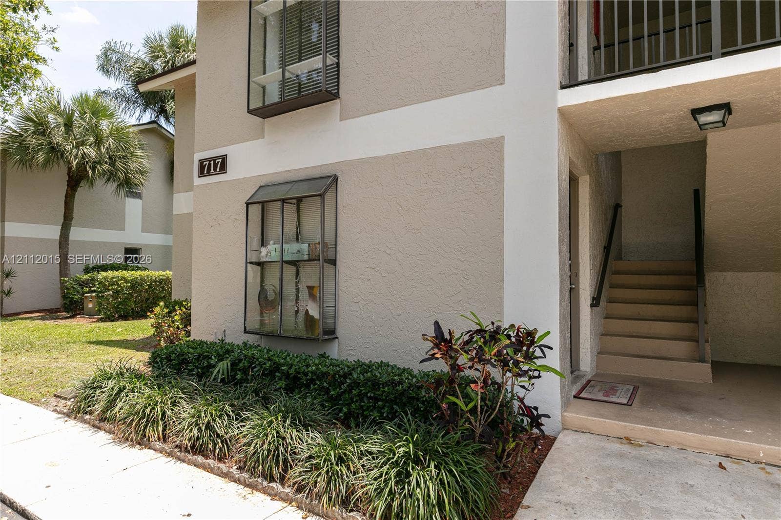 717 Gardens Drive, #201, Pompano Beach, Pompano Beach, FL 33069 Stucco exterior featuring dual-level window boxes, concrete stairs with metal handrails, and low-maintenance landscaping