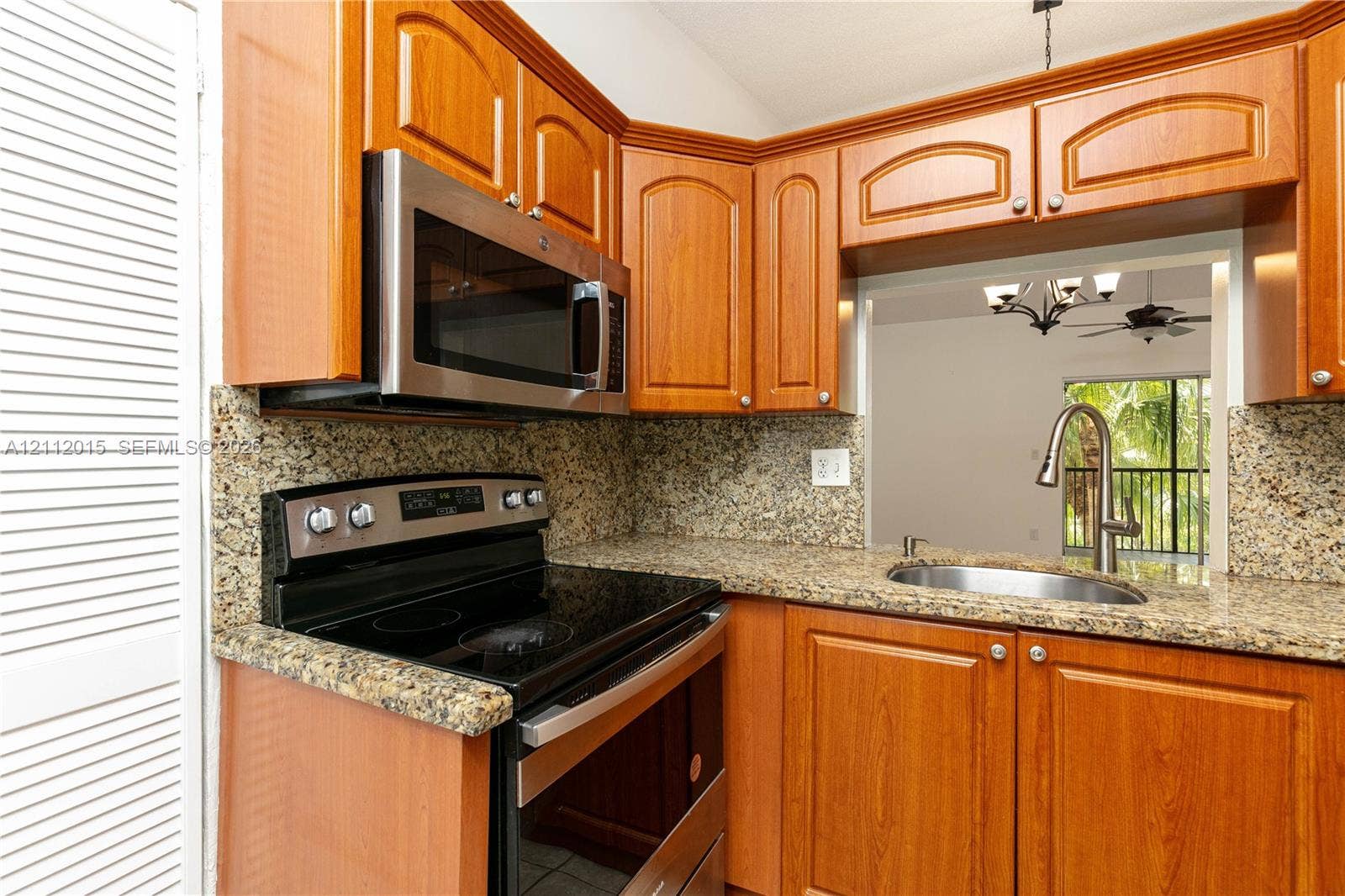 717 Gardens Drive, #201, Pompano Beach, Pompano Beach, FL 33069 Kitchen featuring wood-finish cabinetry, stone-patterned countertops, stainless steel microwave, electric range, and an undermount sink with a high-arch faucet