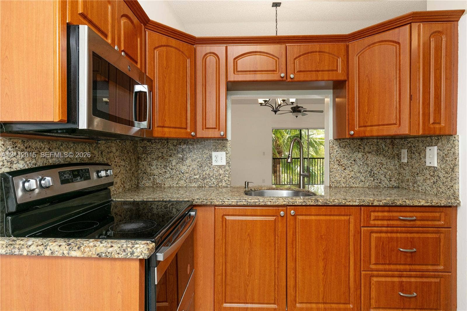 717 Gardens Drive, #201, Pompano Beach, Pompano Beach, FL 33069 Kitchen featuring warm-tone wood cabinetry, stone countertops, stainless steel electric range, built-in microwave, and an undermount sink