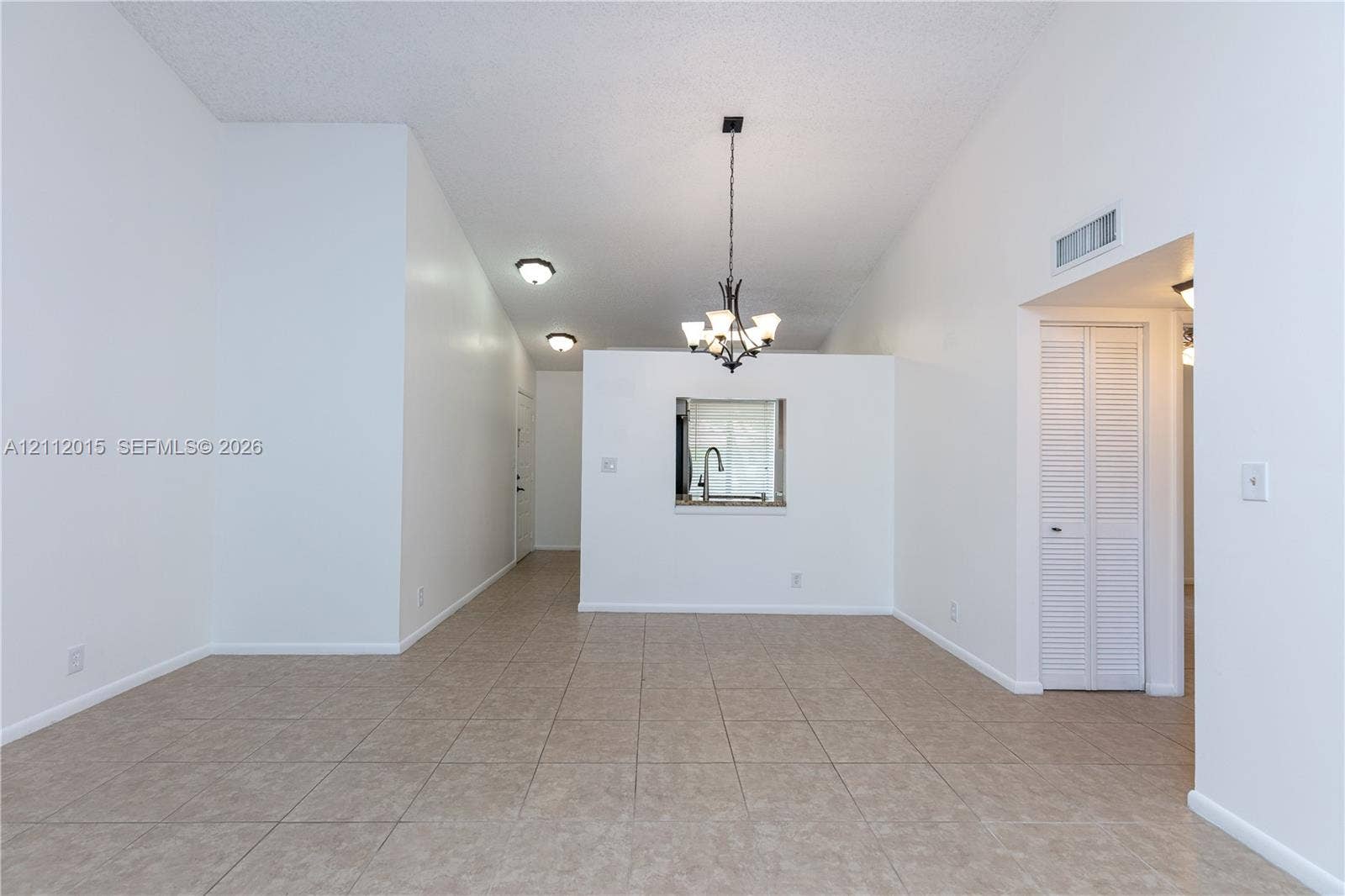 717 Gardens Drive, #201, Pompano Beach, Pompano Beach, FL 33069 Vaulted ceilings, neutral tile flooring, iron-finish chandelier, recessed lighting, and built-in louvered closet doors