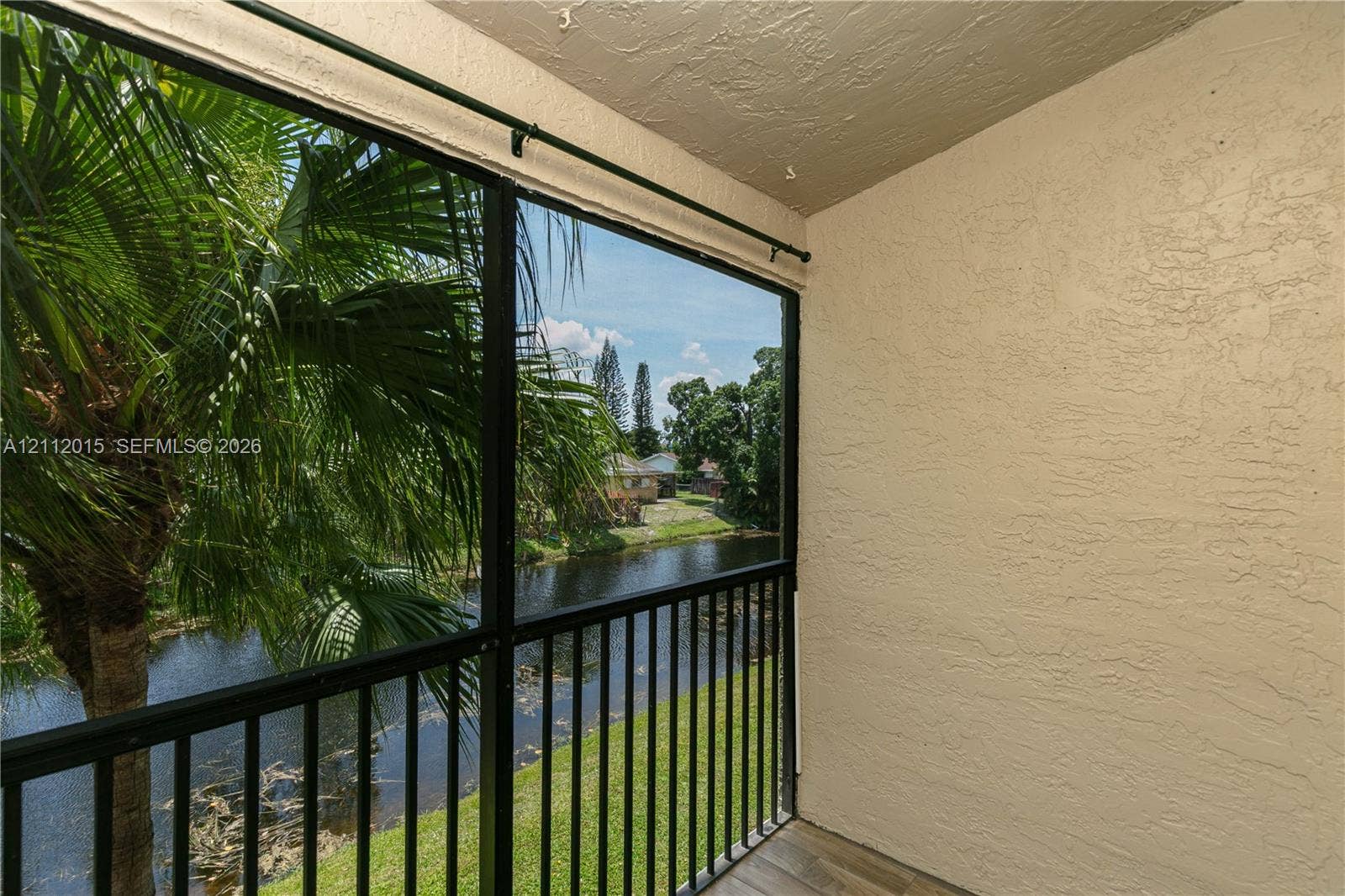 717 Gardens Drive, #201, Pompano Beach, Pompano Beach, FL 33069 Screened-in balcony featuring black metal railings, textured stucco walls, and tile flooring