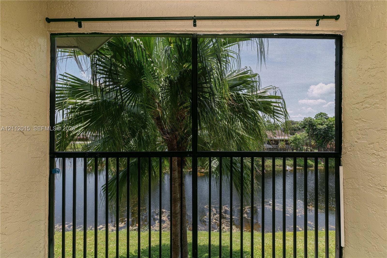 717 Gardens Drive, #201, Pompano Beach, Pompano Beach, FL 33069 Screened-in enclosure featuring a black metal frame, textured wall finishes, and a curtain rod