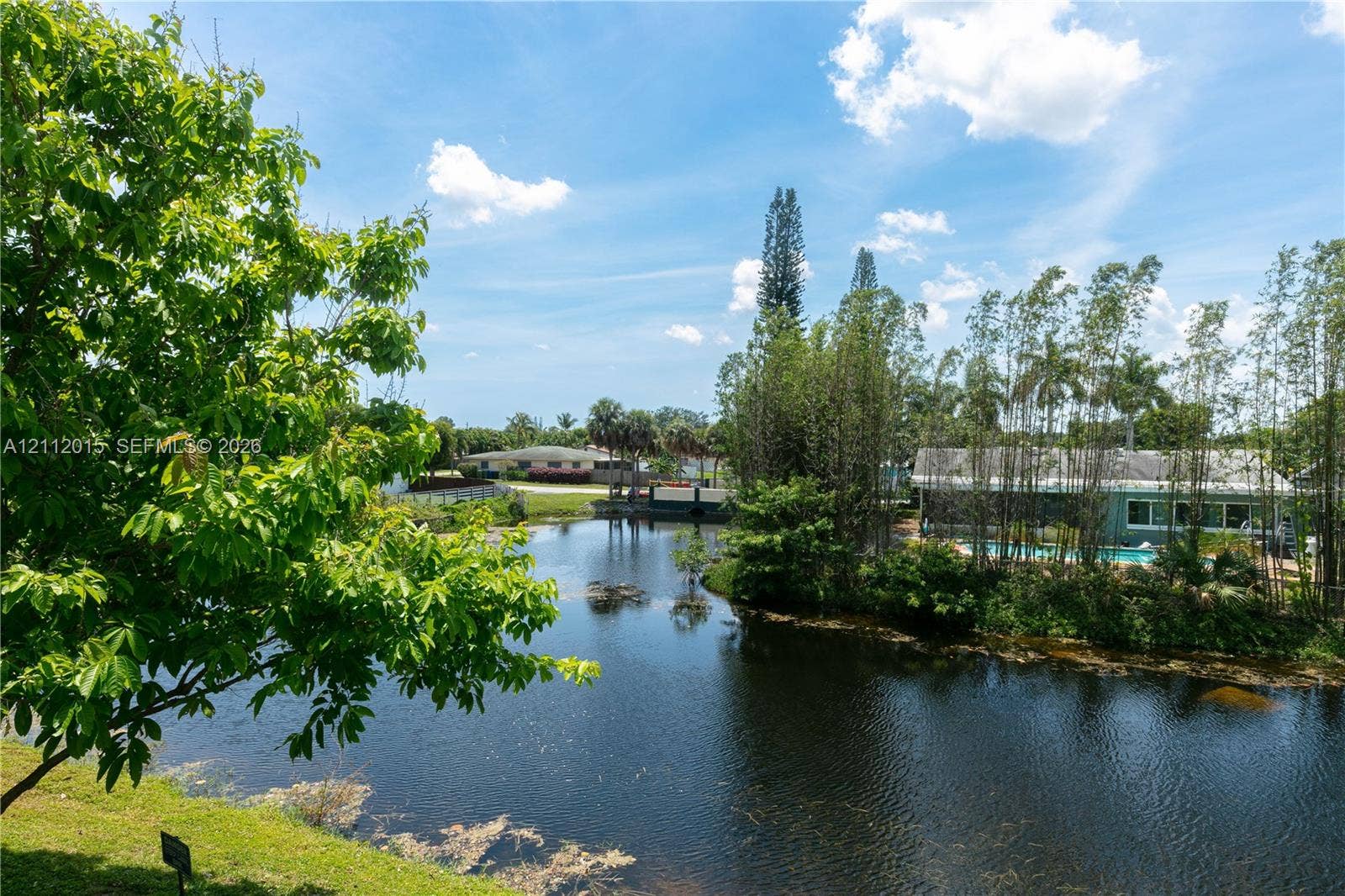 717 Gardens Drive, #201, Pompano Beach, Pompano Beach, FL 33069 Waterfront parcel featuring a natural pond, mature tree canopy, and established landscaping