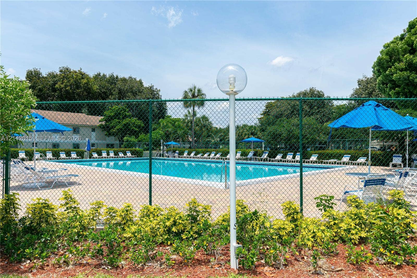 717 Gardens Drive, #201, Pompano Beach, Pompano Beach, FL 33069 Swimming pool with concrete decking, perimeter chain-link fencing, and mature landscaping